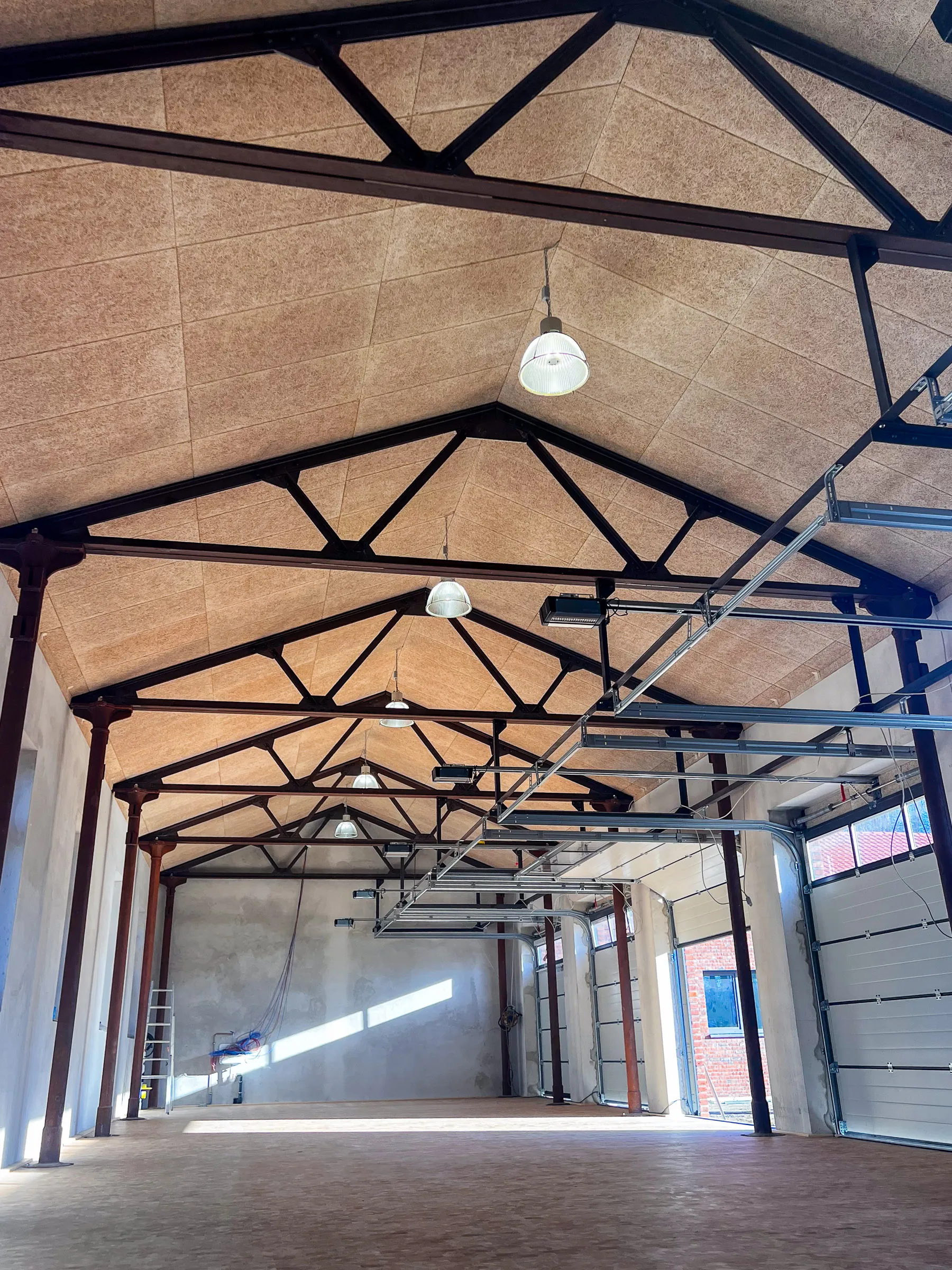 Moderner Deckenbau mit Akustikplatten und sichtbarer Stahlkonstruktion in einer sanierten Industriehalle in Coesfeld