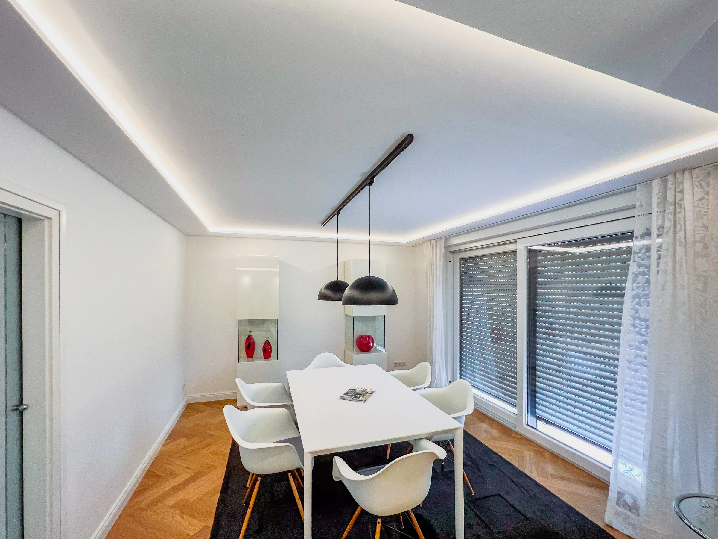 Modernes Esszimmer mit abgehängter Decke und indirekter LED-Beleuchtung – Trockenbau Plus Deckenbauprojekt in Coesfeld mit weißen Wänden, Parkettboden und Design-Pendelleuchten
