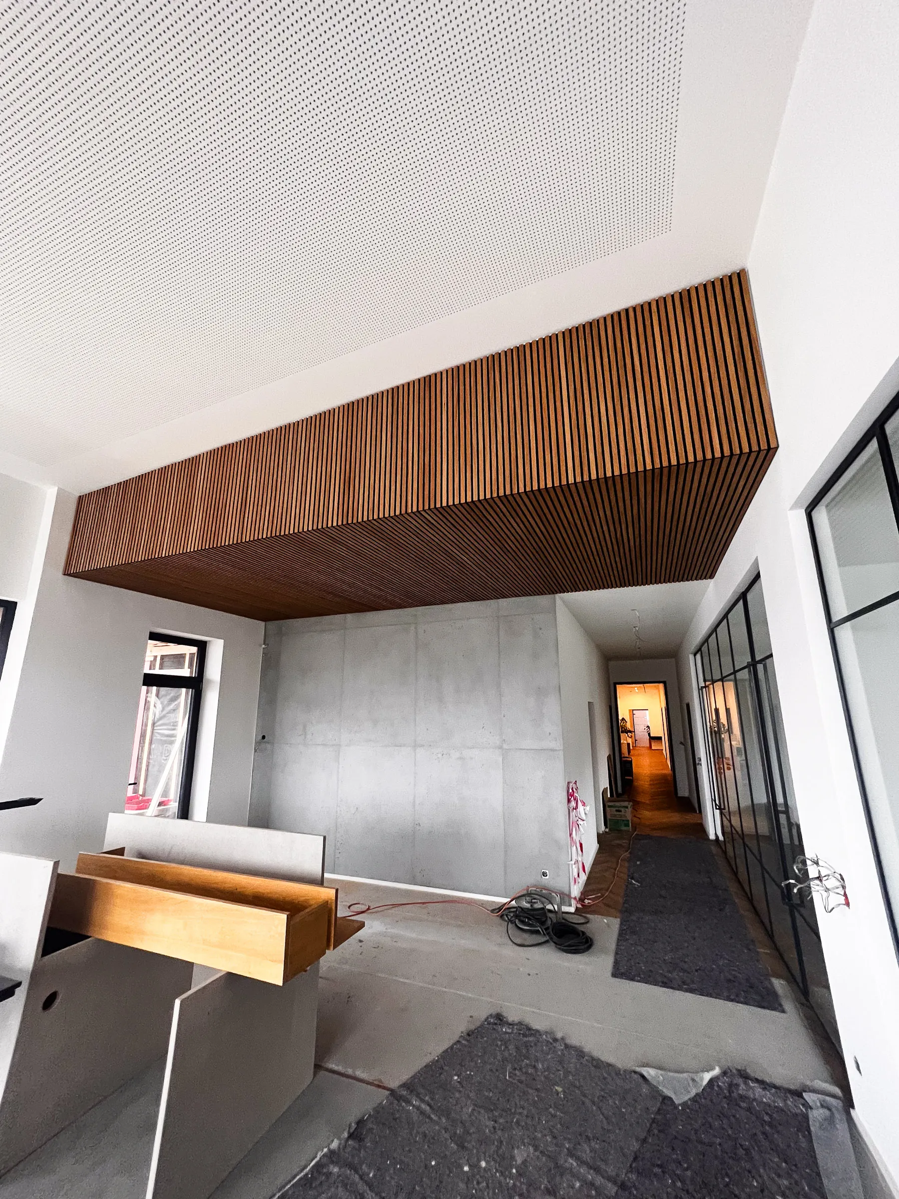 Modernes Akustikbau-Projekt mit Holzlamellen-Decke, gelochter Akustikdecke und Sichtbetonwand – stilvoller Empfangsbereich mit Glasfronten und Trockenbauarbeiten in Coesfeld.