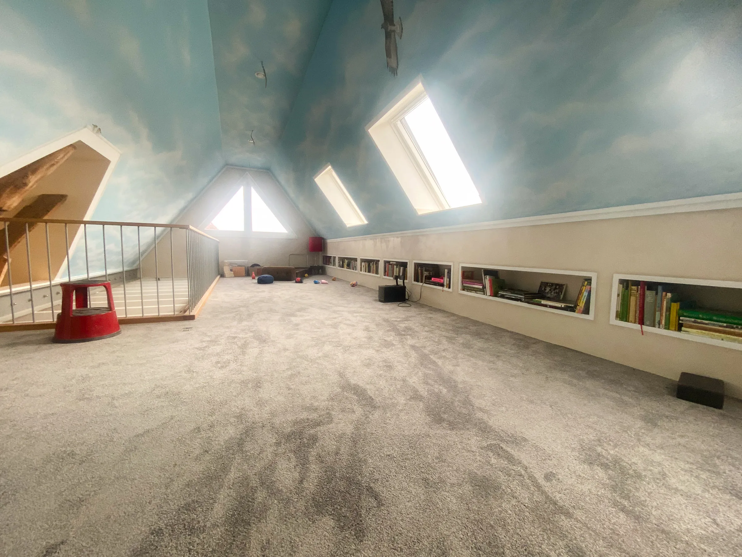 Dachgeschoss-Ausbau mit integriertem Regal, Dachfenstern und wolkenbemalter Decke – individuelles Trockenbau-Projekt von Trockenbau Plus in Coesfeld